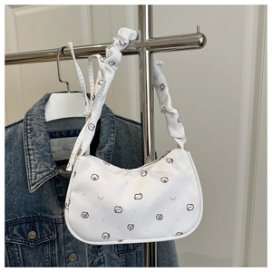 Détail d'un sac demi-lune blanc avec motifs de chat exposé sur un support métallique
