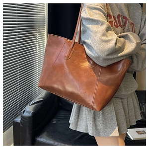 Detail of a vintage brown tote bag in shiny PU leather shown in a stylish urban setting