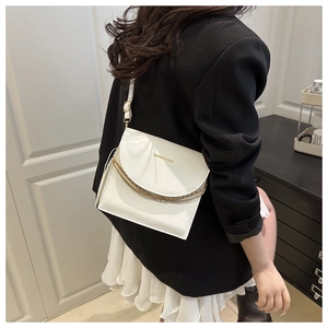 Close-up of a white square crossbody bag with gold chain and fashion logo on model