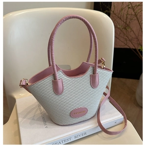 Close-up of pink leather and woven bucket bag texture with an oval fashion label detail