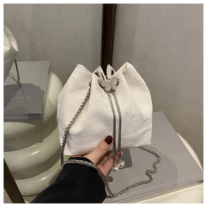 Close-up of white satin bucket bag with silver butterfly buckle and pearl charms