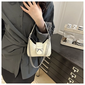 Détail d'un sac demi-lune blanc crème avec nœud argenté et fine bandoulière en métal