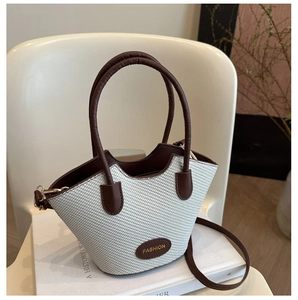 Detailed view of woven texture and brown leather trim on a minimalist bucket bag