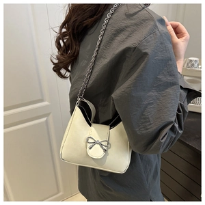 Détail du sac croissant beige avec nœud argenté et bandoulière en chaîne métal