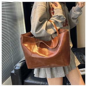 Detailed side view of a brown vintage tote bag showing its shiny leather texture and stitching