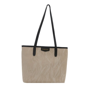 Chic beige textured tote bag with black handles and fashion tag for 2025 spring style