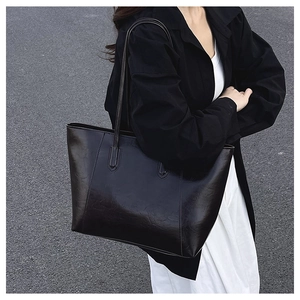 Side view of large black retro PU leather tote bag worn with a casual office outfit