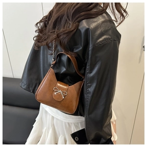Détail du sac croissant marron avec boucle nœud argenté et texture en cuir