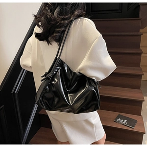 Macro detail of black glossy tote bag with drawstring texture and knotted shoulder strap