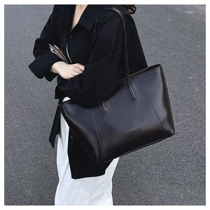 Detail view of a large vintage brown tote bag worn on shoulder for daily commute