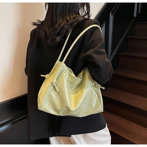 Close-up of a pistachio green patent leather shoulder bag with side drawstring details