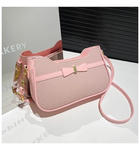 Detail of pink patchwork underarm bag featuring a woven texture and leather bow accent