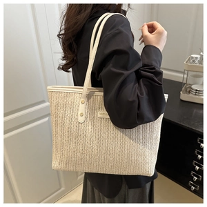 Dettaglio di una borsa tote in paglia color crema con trama intrecciata e etichetta moda