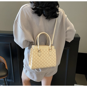 Detail of beige letter print handbag with shoulder strap showing fashion bag textures
