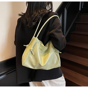 Detail of light green patent leather shoulder bag with glossy finish and knot details