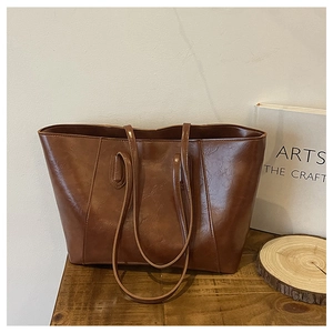Close-up of brown vintage faux leather tote bag showing glossy texture and creased detail