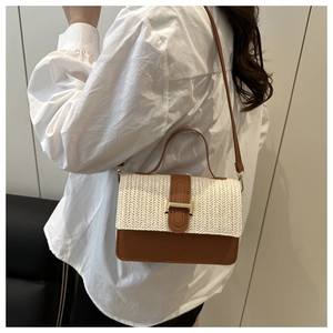 Close-up of contrast woven handbag with brown leather trim and golden H-shaped clasp