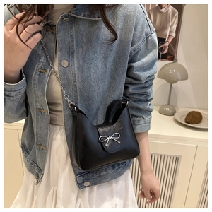 Détail du sac croissant noir avec nœud en métal argenté et bandoulière en chaîne
