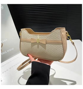 Detail of beige woven texture bag with gold metal buckle and elegant bow decoration