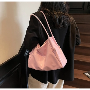 Pink glossy shoulder bag with knot detail shown on a model for a casual look