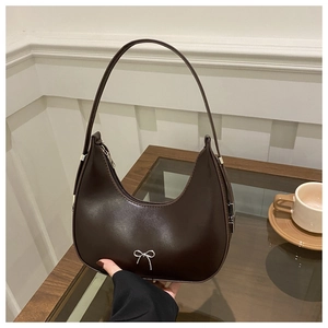 Detail of dark brown crescent bag with silver bow hardware and zipper closure