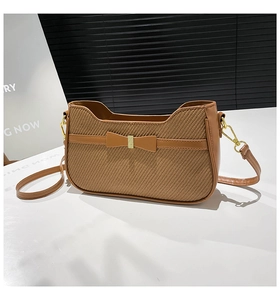 Detail of brown woven texture bag with leather bow and golden metal hardware