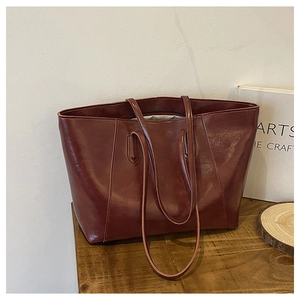 Close-up of burgundy oil-wax leather tote bag on a wooden table with vintage aesthetic