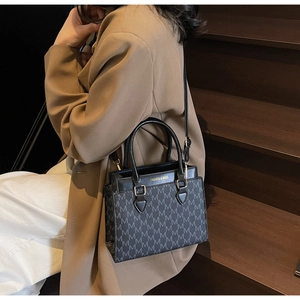 Detail of square crossbody bag with grey monogram pattern and golden hardware details