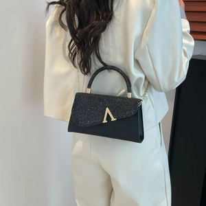 Minimalist black crossbody bag with glitter flap and golden V-shaped metal buckle detail