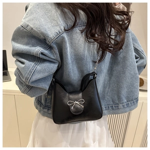 Détail du sac croissant en cuir noir avec nœud argenté et bandoulière en chaîne