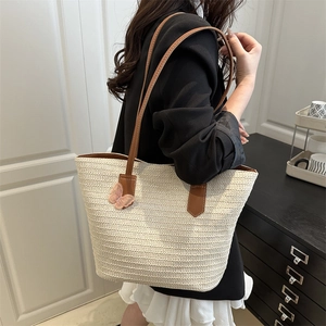 Large beige woven straw tote bag with brown leather straps and pink butterfly charm