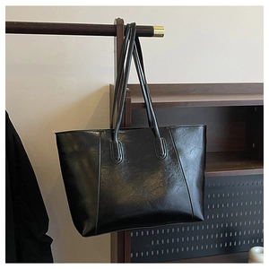 Detailed view of the wrinkled texture and stitching on this black matte tote bag