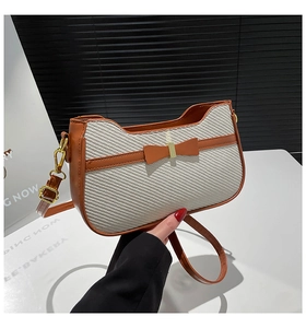 Detail of caramel fabric woven bag featuring leather bow and golden metal hardware hooks