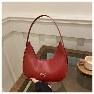 Detail view of red crescent hobo bag featuring a silver bow buckle and smooth texture