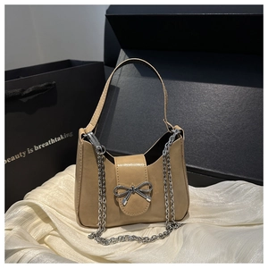 Détail du sac croissant beige avec boucle nœud argenté et bandoulière en chaîne