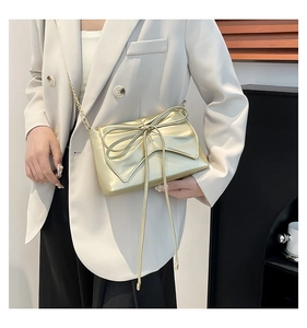 Detail of champagne gold crossbody bag with metallic bow and elegant chain strap