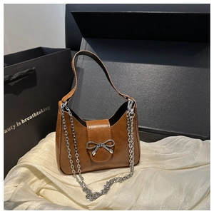 Détail macro du sac croissant marron avec boucle nœud argentée et bandoulière chaîne