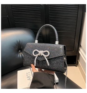 Détail du sac à main noir pailleté avec boucle nœud strass et bandoulière chaîne