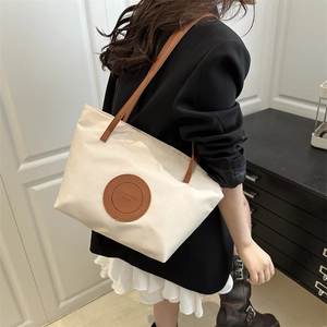 Fashionable cream tote bag with brown leather straps shown on a model for daily commute