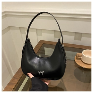 Detail of black crescent hobo bag featuring a silver metal bow buckle and zipper closure