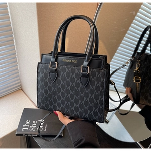 Detail view of square crossbody bag with jacquard M-pattern and gold hardware accents