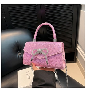 Détail d'un sac bandoulière rose à paillettes avec un nœud en strass étincelant