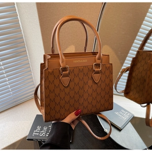 Detail of brown square crossbody bag with M-pattern print and gold-tone hardware