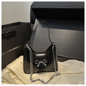 Détail du sac croissant noir avec boucle noeud argenté sur fond en satin doux