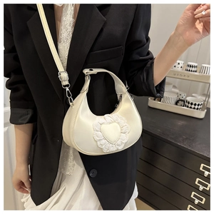 Detailed view of cream crescent bag featuring heart lace trim and silver buckle