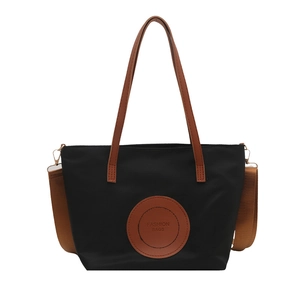 Minimalist black nylon tote bag with brown leather labels and detachable shoulder straps
