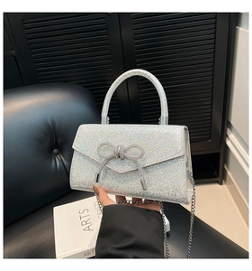 Détail du sac à main à paillettes argentées avec nœud en strass et chaîne métallique