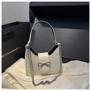Détail du sac croissant crème avec boucle nœud argenté et bandoulière en chaîne
