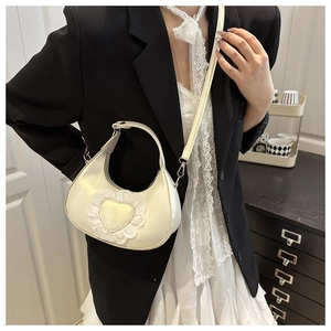 Close-up of cream hobo bag featuring delicate heart lace applique shown on shoulder