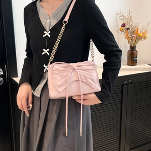 Pink ribbon crossbody tote bag with chic chain strap shown in a stylish interior setting